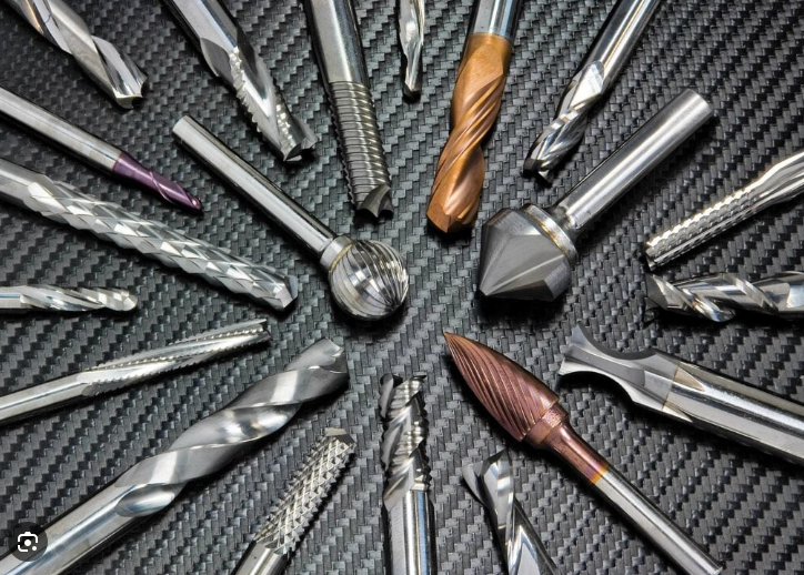 Drill bits and cutting tools arranged on a black textured surface.