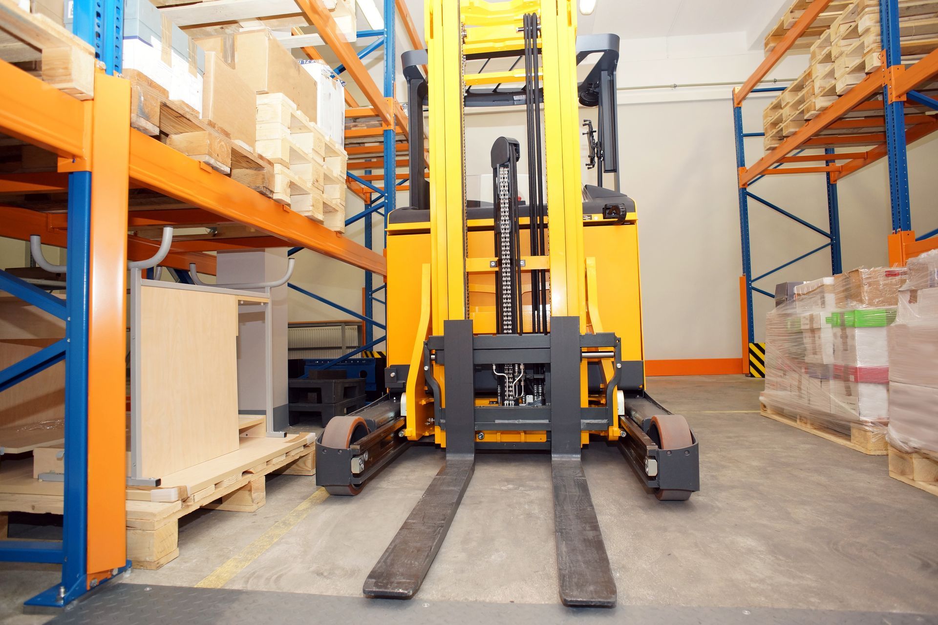 Forklift in a warehouse, with pallets of boxes on shelves.